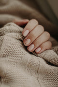 Ongles naturels soignés sur un tricot beige