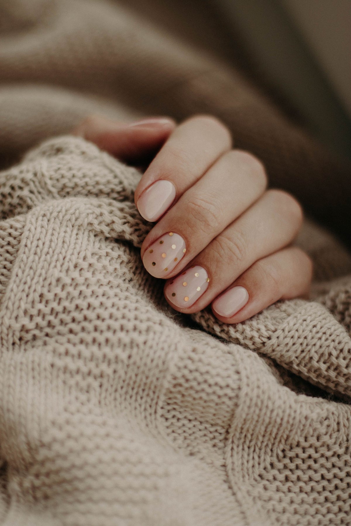 Ongles naturels soignés sur un tricot beige