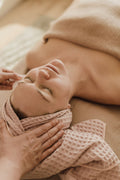 Mains aux tempes d'une cliente pendant un soin du visage